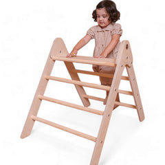 Kind spielt auf dem klappbaren Pikler Kletterdreieck aus Holz, Montessori Motorikspielzeug für kreative Bewegung.
